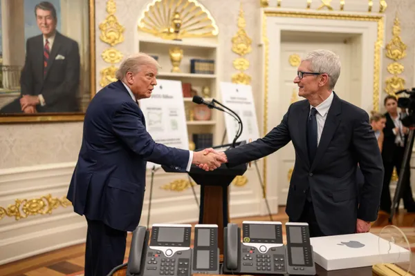 President Trump shakes hands with Apple CEO Tim Cook in the Oval Office during the $100 billion investment announcement.