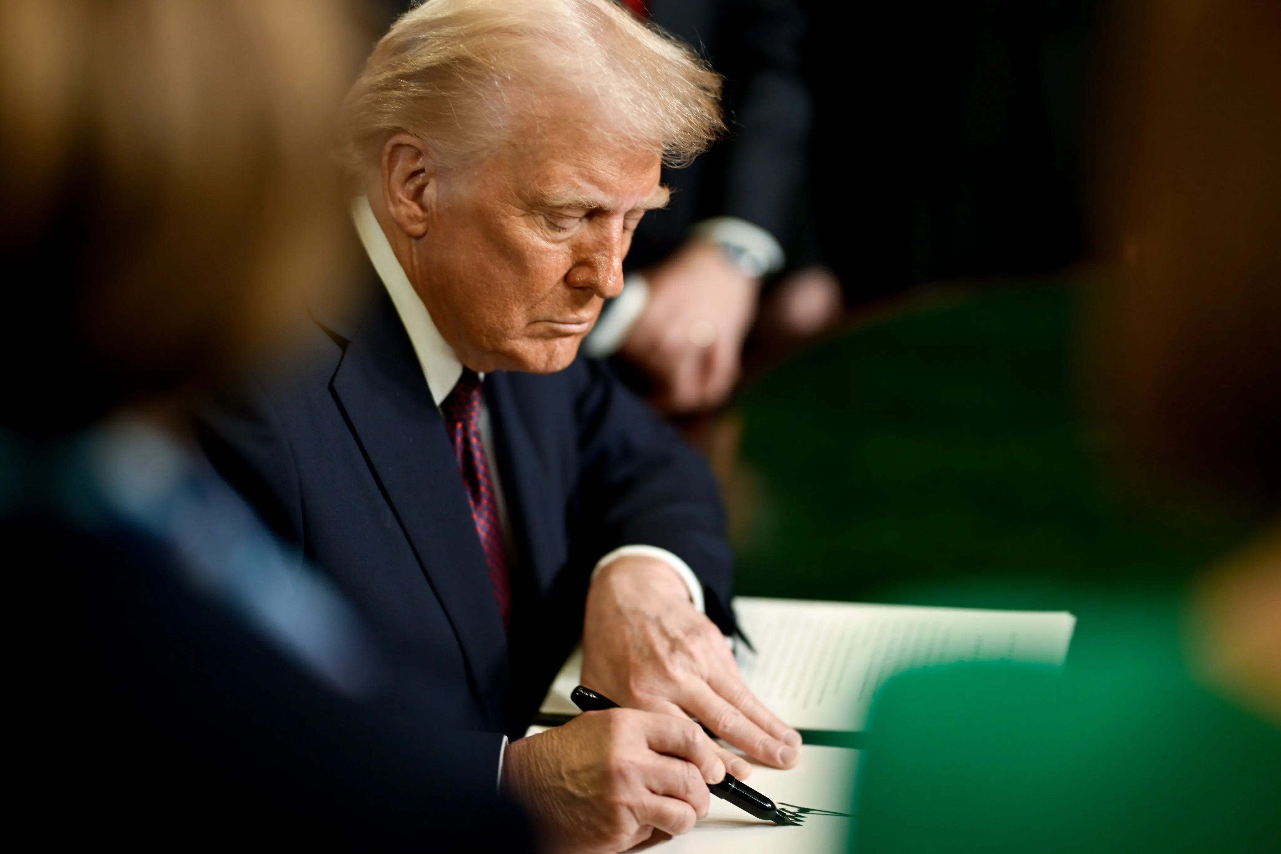 President Donald J. Trump signing executive orders at the Resolute Desk in the Oval Office.