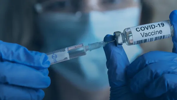 Hands handling a vaccine vial and syringe